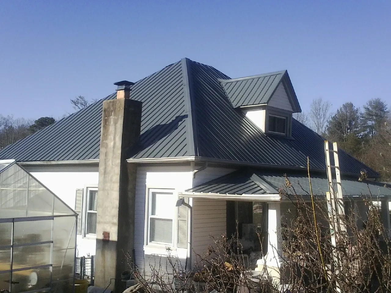Dark blue standing seam metal roof on a white farmhouse with dormer — Slate & Tile Roof Repair by Roofing Brothers in Caldwell