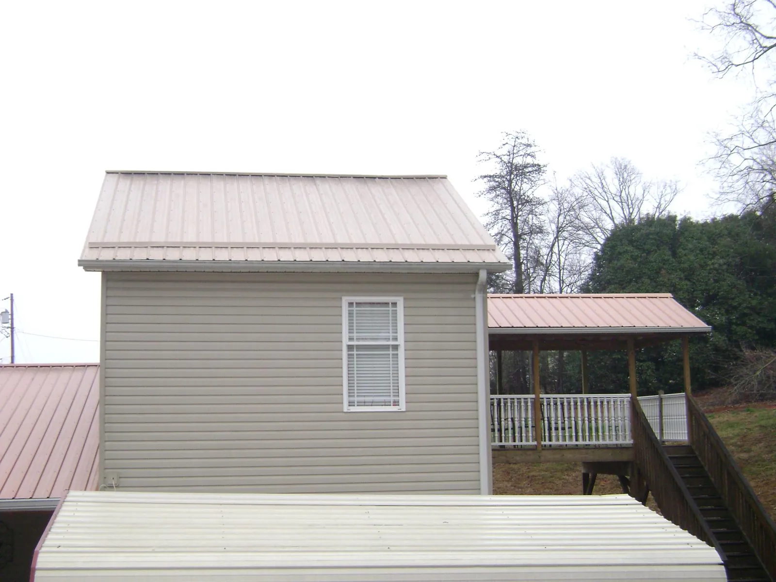 Tan metal roofs on a two story addition and attached porch, from a Roof Replacement job in Caldwell